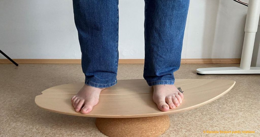 Zwei Füße auf einem Balance Board, die auf einer Korkkugel stehen.