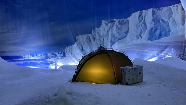 Beleuchtetes Kuppelzelt in einer nächtlichen, antarktischen Umgebung.